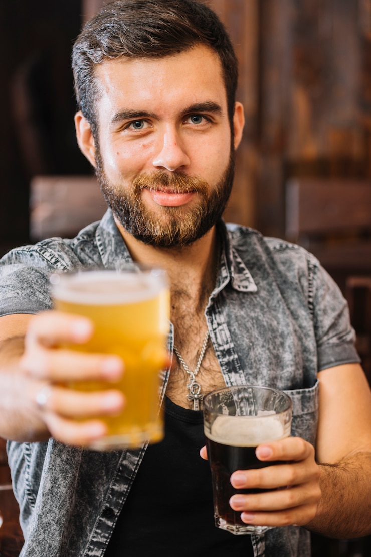 Foto gratuito primo piano di un uomo che tiene i bicchieri di birra e rum