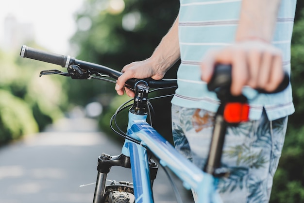 Primo piano di un uomo in piedi con la bicicletta all&#39;aperto