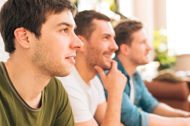 Primo piano di un uomo seduto con gli amici a guardare la televisione