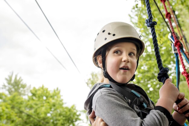 Primo piano di una bambina caucasica che indossa un casco bianco appeso alla corda