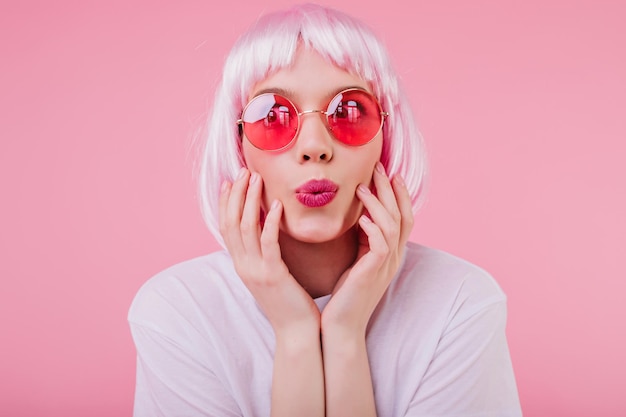 Primo piano di una bella donna di buonumore con occhiali da sole rosa Foto interna di una ragazza europea alla moda indossa peruke