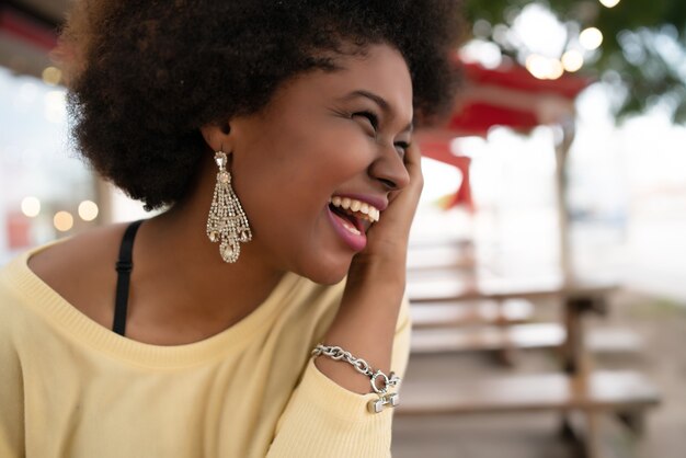 Primo piano di una bella donna latina afroamericana sorridente e trascorrere del bel tempo presso la caffetteria.