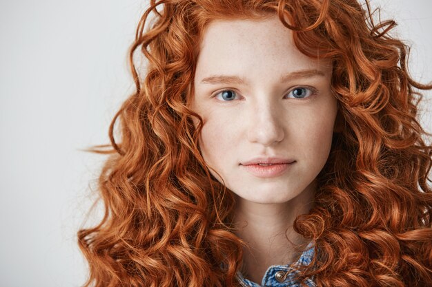 Primo piano di una bella ragazza con i capelli rossi ricci e le lentiggini.