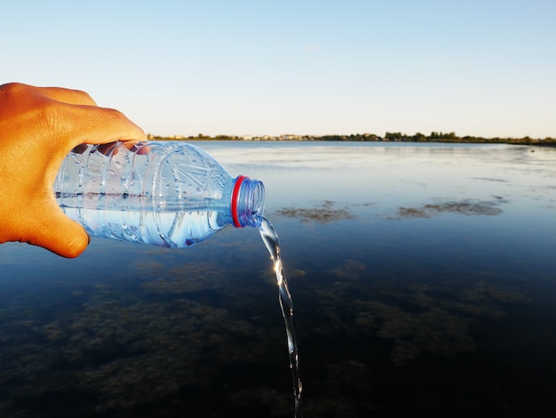 Primo piano di una bottiglia d'acqua di plastica in una mano umana perfetta per il concetto di spreco d'acqua