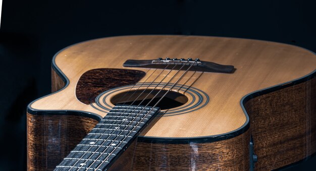 Primo piano di una chitarra acustica classica su sfondo nero.