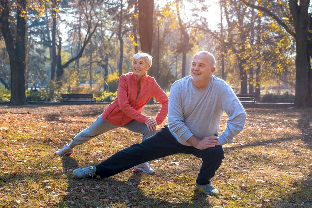 Primo piano di una coppia senior caucasica sorridente che si esercita in un parco in una soleggiata giornata autunnale