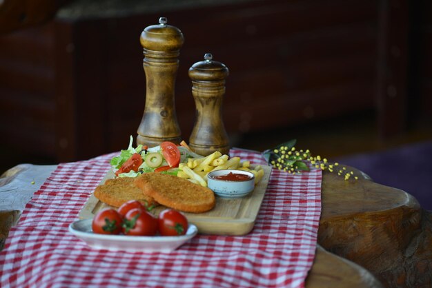 Primo piano di una deliziosa colazione di patatine fritte polpette di pesce fritto insalata e salsa sul tavolo