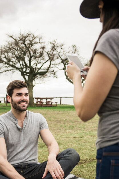 Primo piano di una donna che cattura maschera di un uomo sulla macchina fotografica digitale nel parco