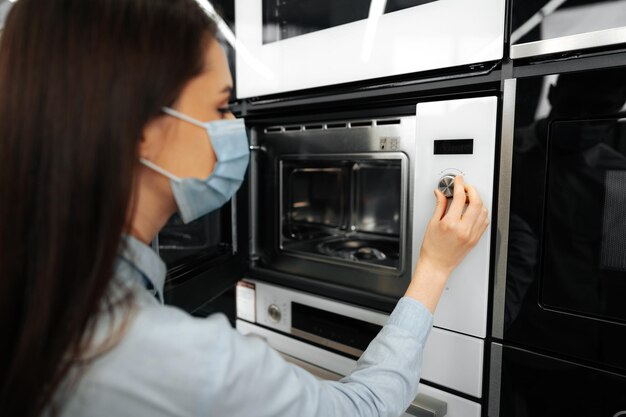 Primo piano di una donna che controlla il nuovo forno a microonde in un ipermercato