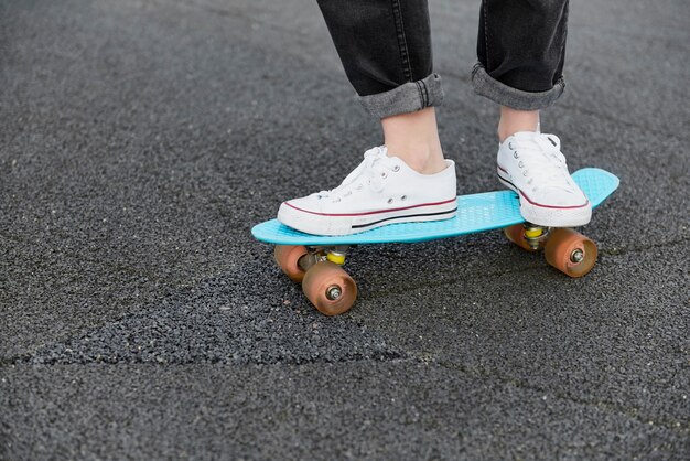 Primo piano di una donna hipster in piedi sullo skateboard