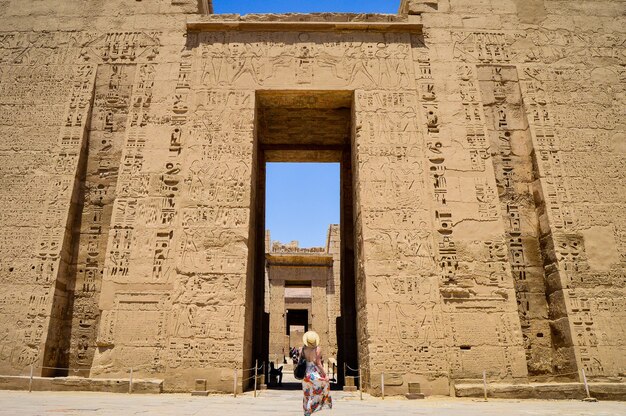 Primo piano di una donna in piedi di fronte a un tempio di Medinet Habu in Egitto