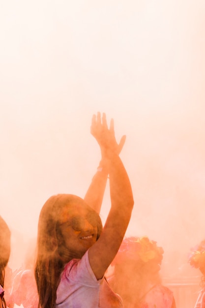 Primo piano di una donna sorridente che balla nel colore holi