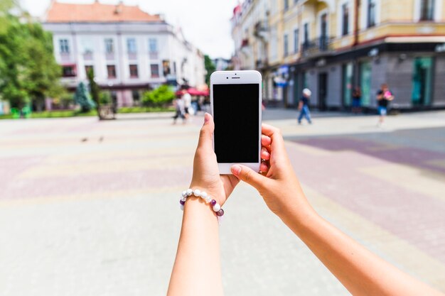 Primo piano di una femmina di scattare una foto della strada urbana attraverso il cellulare