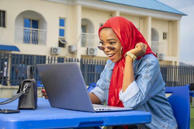 Primo piano di una giovane donna afroamericana che guarda con entusiasmo lo schermo del suo laptop