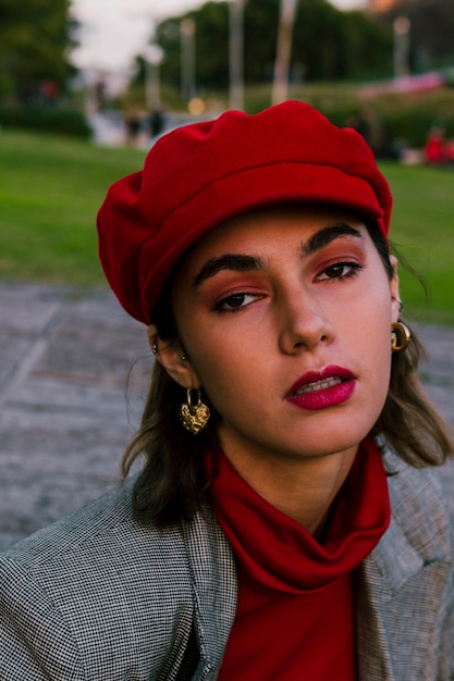 Primo piano di una giovane donna attraente con il berretto rosso sopra la sua testa che guarda l&#39;obbiettivo