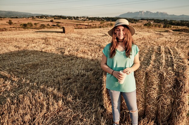 Primo piano di una giovane ragazza con cappello rotondo in piedi e guardando la telecamera