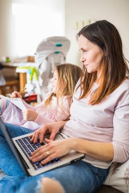 Primo piano di una madre con il computer portatile che esamina le sue note di scrittura del bambino a casa