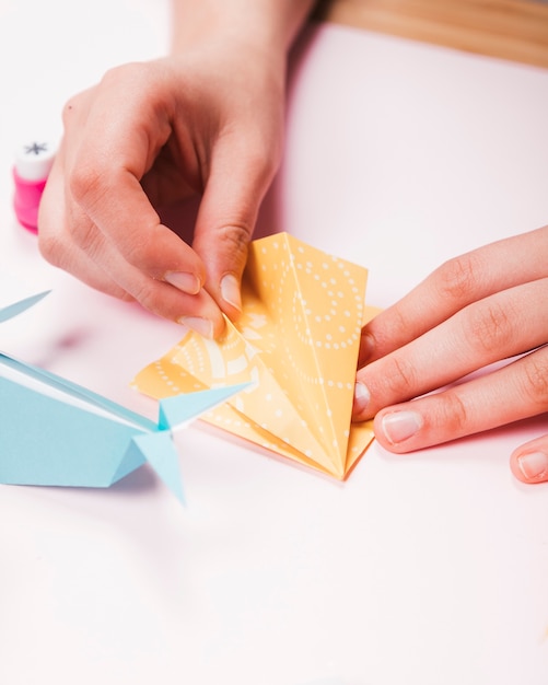Primo piano di una mano umana che fa uccello di origami