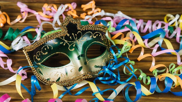 Primo piano di una maschera di carnevale con stelle filanti colorate sullo scrittorio di legno