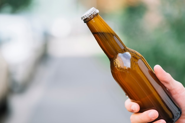 Primo piano di una persona che tiene la bottiglia di birra