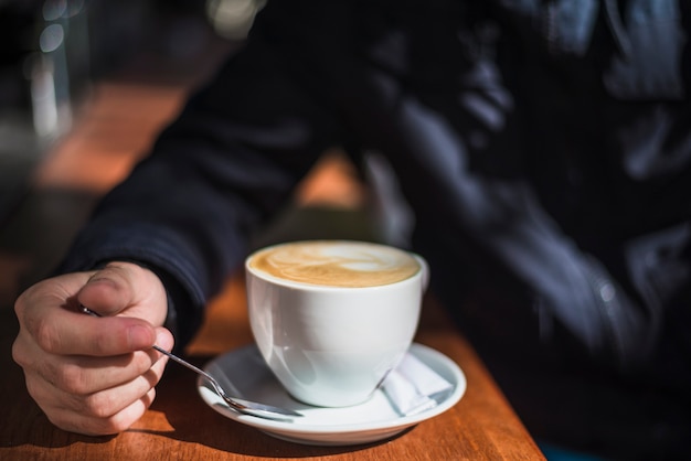 Primo piano di una persona con una tazza di caffè caldo espresso sul tavolo