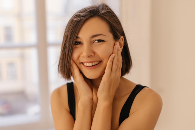 Primo piano di una ragazza caucasica carina con un sorriso bianco come la neve e capelli scuri su sfondo bianco Concetto di persone e tempo libero