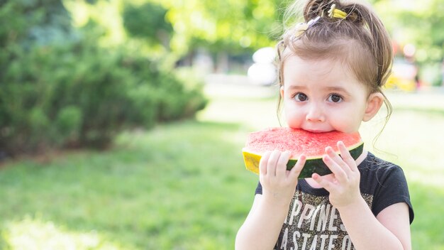 Primo piano di una ragazza che mangia anguria nel parco