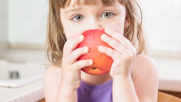 Primo piano di una ragazza che mangia mela rossa matura