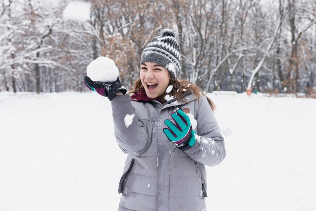 Primo piano di una ragazza felice che gioca con la neve nella foresta