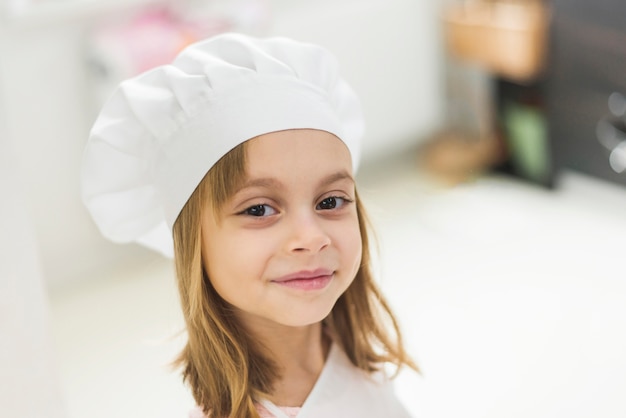 Primo piano di una ragazza sorridente carina che indossa cappello da cuoco