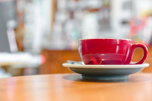 Primo piano di una tazza di caffè rossa sullo scrittorio di legno