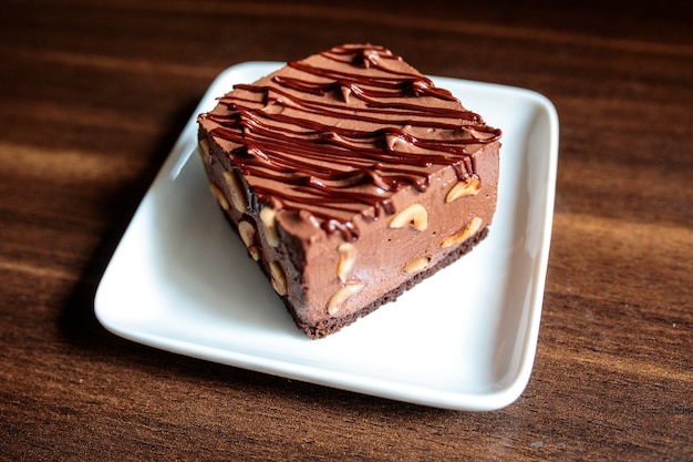 Primo piano di una torta umida al cioccolato con anacardi su un piatto quadrato bianco