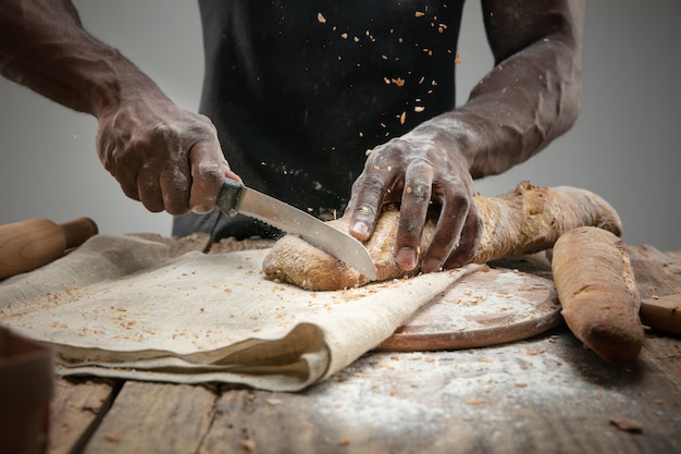 Primo piano di uomo afro-americano fette di pane fresco con un coltello da cucina