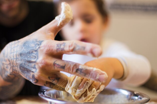 Primo piano di uomo con figlio impastare la pasta