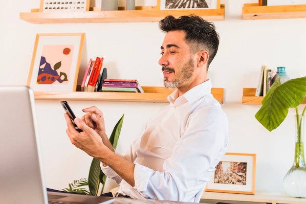 Primo piano di uomo d&#39;affari utilizzando il telefono cellulare in ufficio