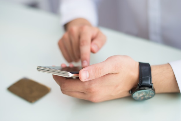 Primo piano di uomo irriconoscibile con orologio da polso tramite smartphone