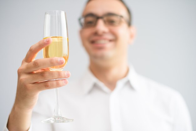 Primo piano di uomo sorridente che solleva calice con champagne