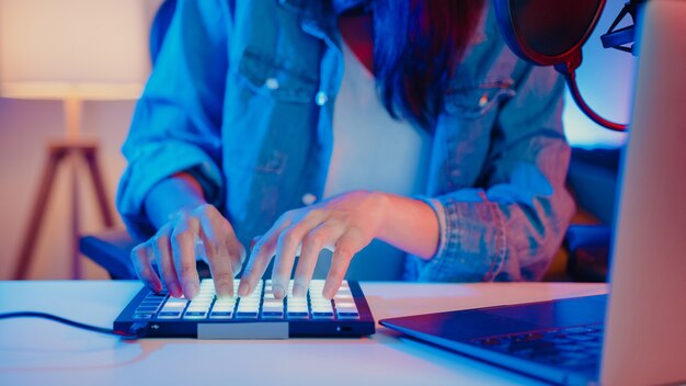 Primo piano felice ragazza asiatica dj utilizzando la tastiera del sintetizzatore launchpad