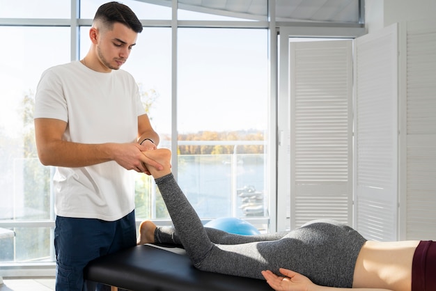 Primo piano fisioterapista che massaggia il piede