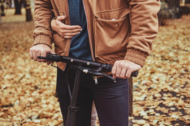 Primo piano fotografico di uomo e donna sullo scooter al parco autunnale.