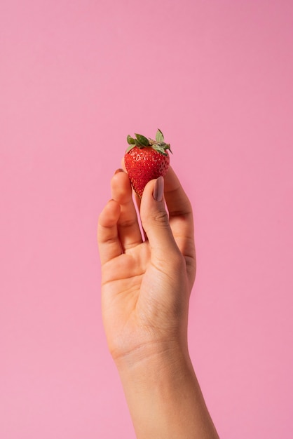 Primo piano mano che tiene fragola