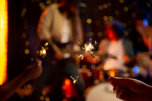 Primo piano mano che tiene fuochi d'artificio al concerto