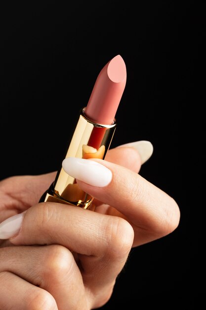 Primo piano mano che tiene rossetto rosa