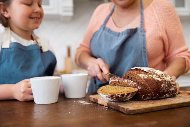 Primo piano nonna che taglia il pane