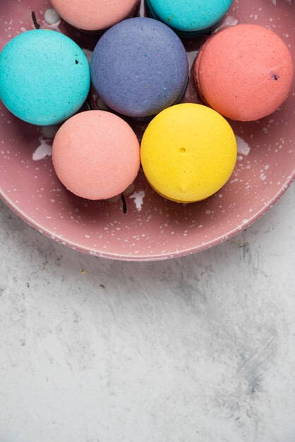 Primo piano piatto di macarons pastello su superficie bianca.