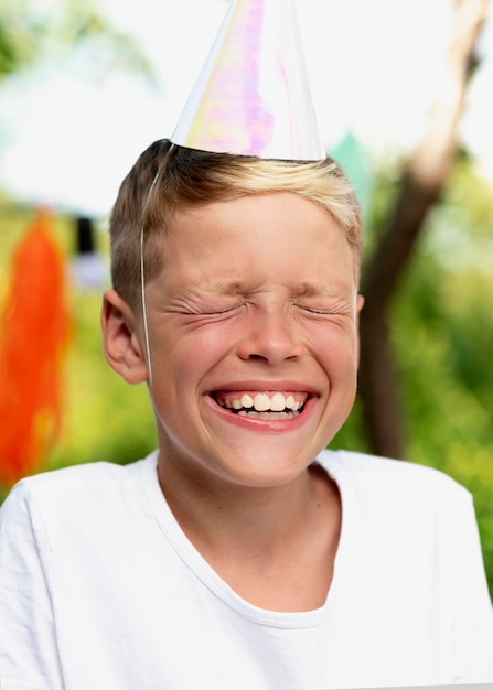 Primo piano ragazzo sorridente con cappello da festa