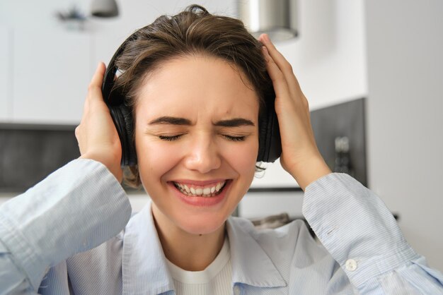 Primo piano ritratto di donna che si emoziona dalla musica che ascolta la canzone in cuffie wireless smi