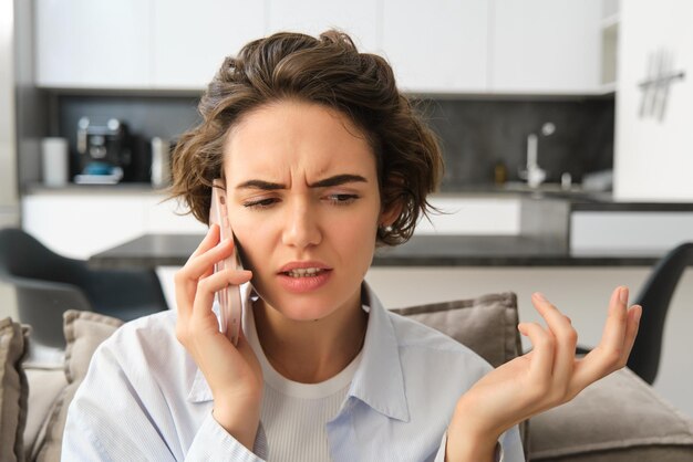 Primo piano ritratto di giovane donna confusa risponde alla telefonata e alza le spalle sembra perplesso mentre ascolta