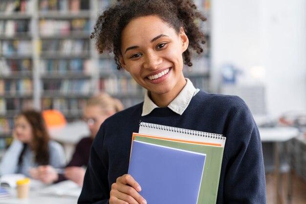 Primo piano sorridente studente in possesso di libri