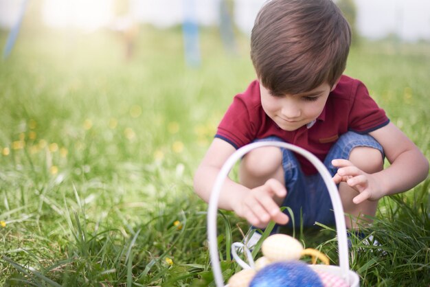 Primo piano sul giovane ragazzo guardando le uova di Pasqua colorate